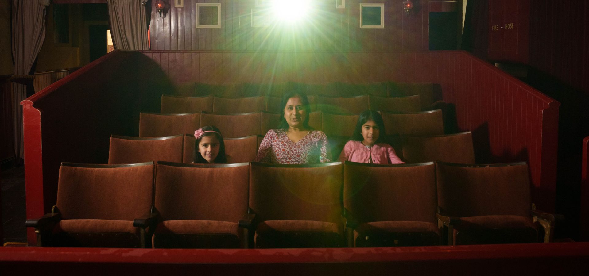 An adult and 2 children in cinema seating