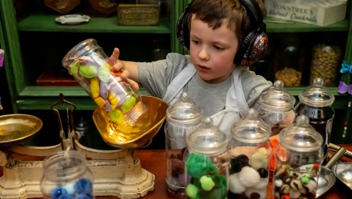 A child weighing pom pom sweets in clear containers