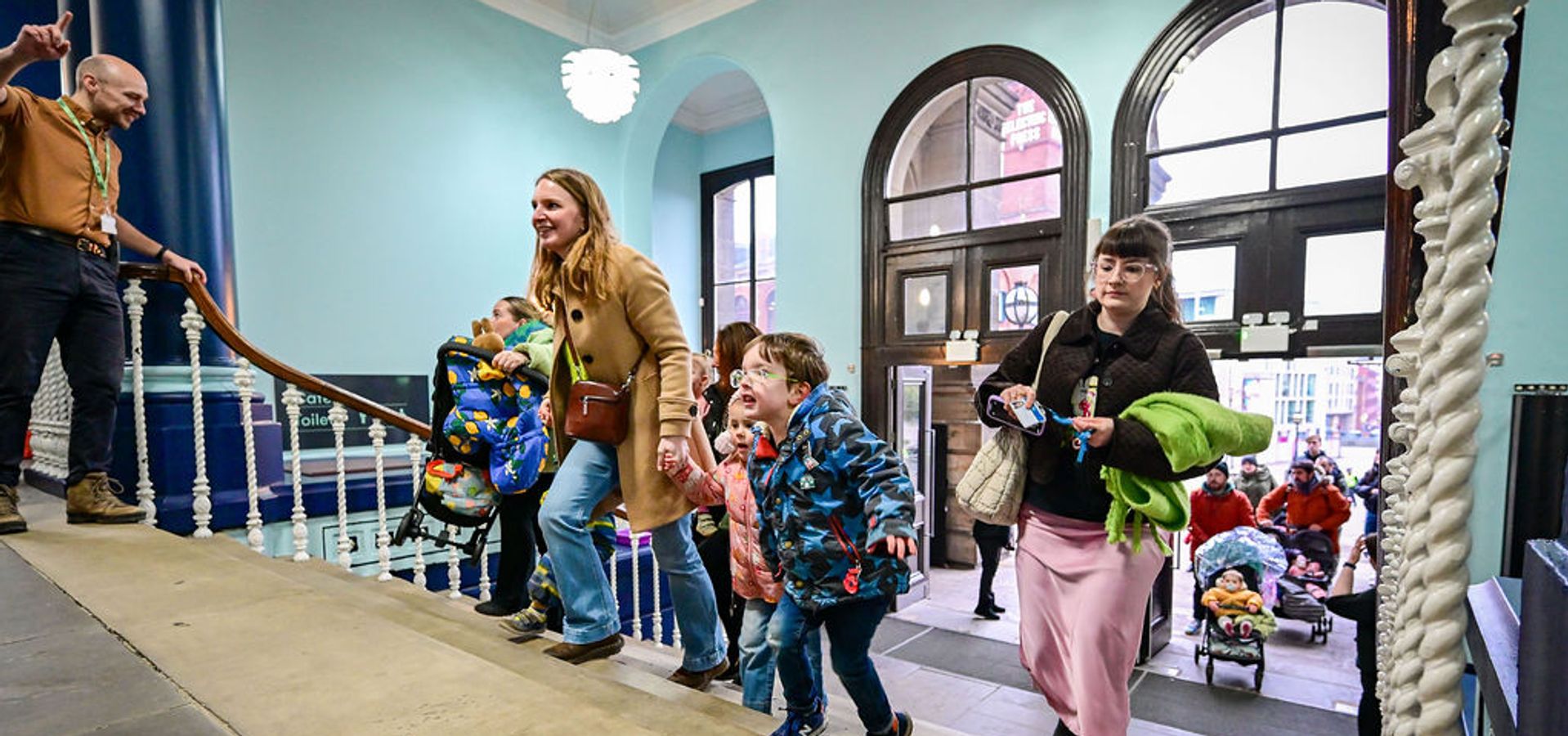 A family walking up the stairs into Leeds City Museum