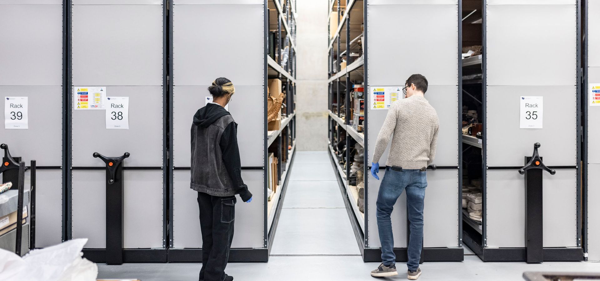 Two people rotating storage shelves in Leeds Discovery Centre