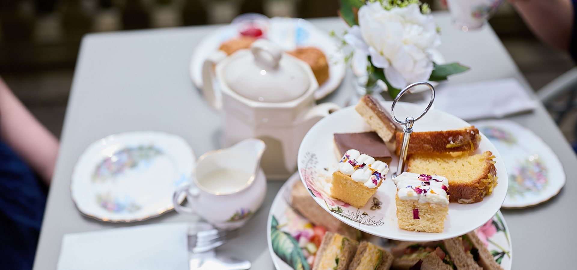 a cake stand with afternoon tea on and cutlery and plates on the table