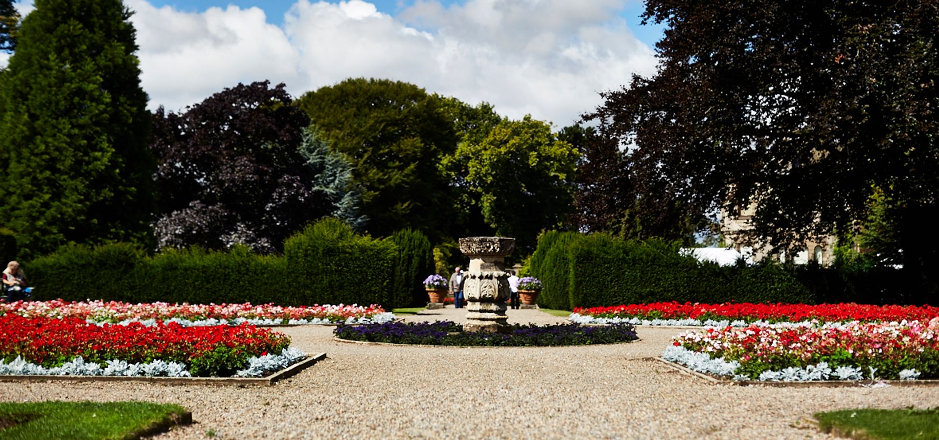 A stone pillar in a circle, with a pathway around and flower beds on all sides