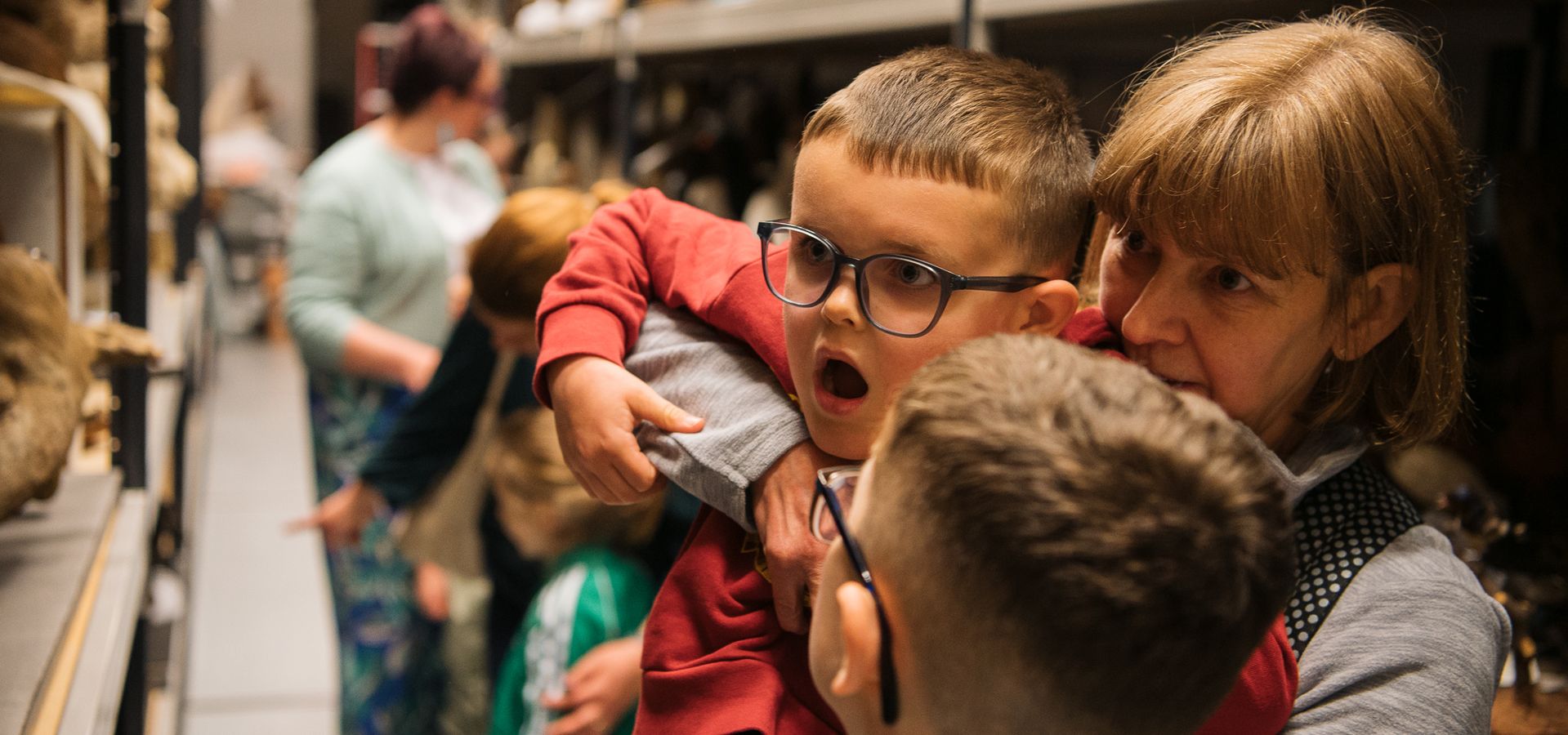an adult holding a child up to look at an object