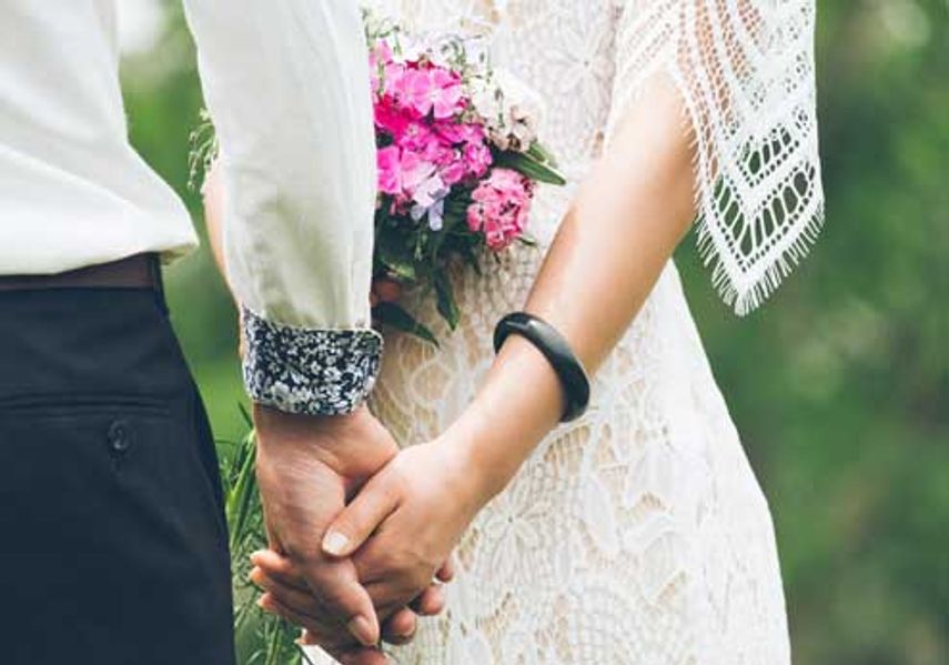 A newly married couple hold hands. 