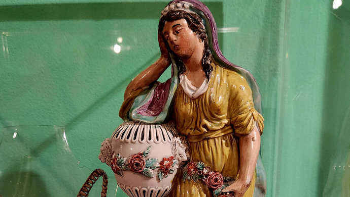 A close up image of a ceramic woman looking mourningful