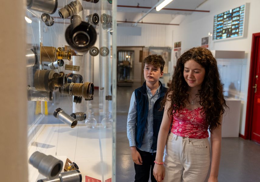 Two children looking at a display cabinet with camera pieces hanging in