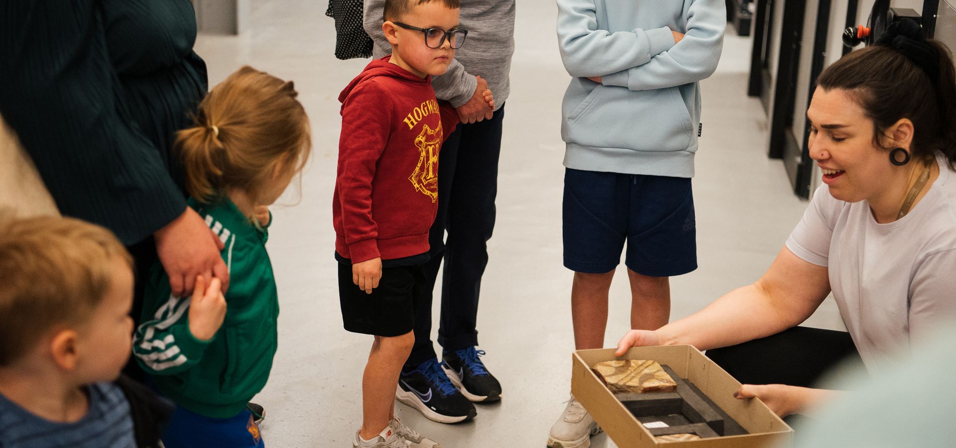 A curator holding a box of ancient tiles in front of a tour group