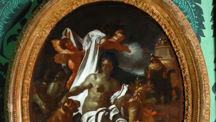 An oval frame hung on green patterned wallpaper. The frame picture is Africa by F Solimena