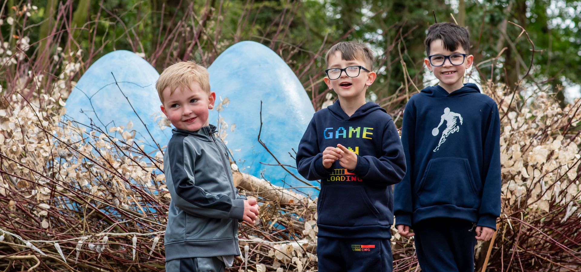 Photo of 3 young boys stood in front of a giant nest of blue eggs