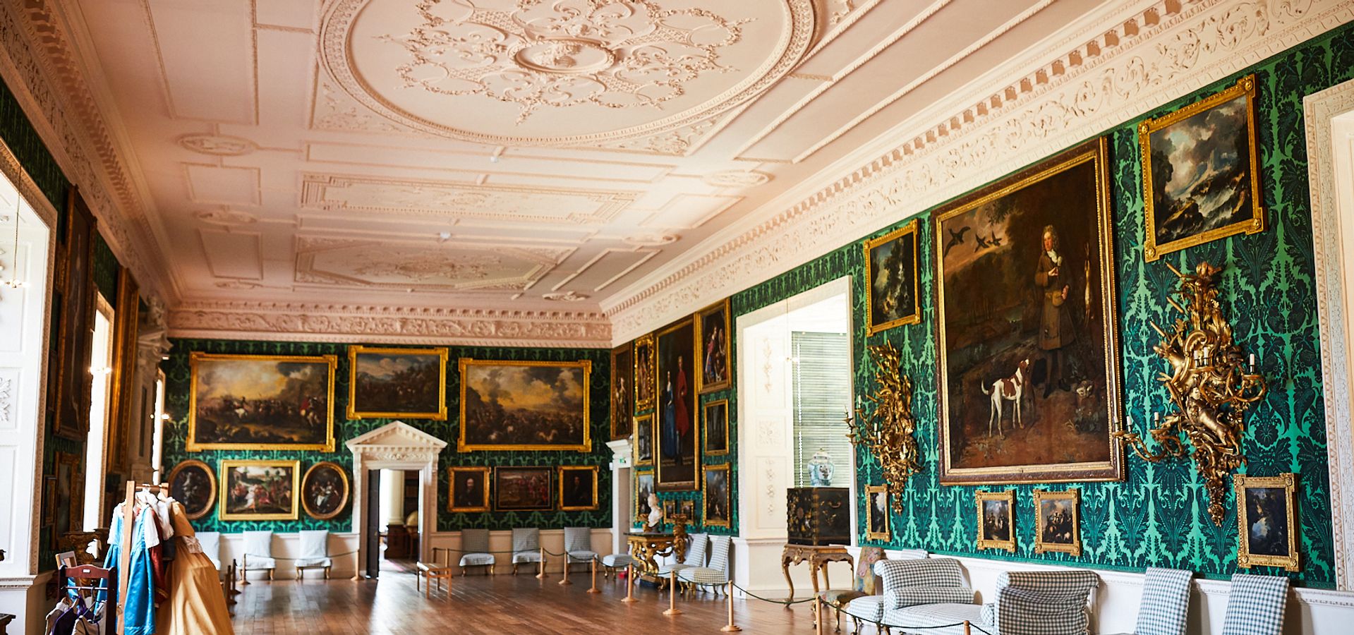 The picture gallery, with high ceilings and green walls with portraits hanging on them