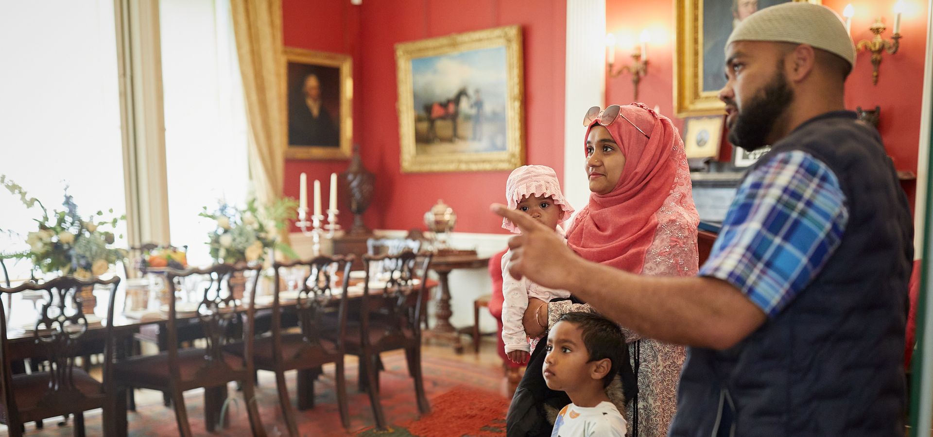 A family looking around a red Edwardian dining room