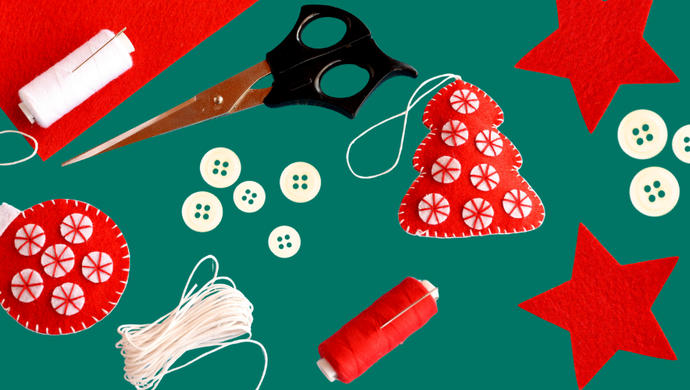 felt tree and bauble shaped ornaments with thread, buttons and scissors surrounding