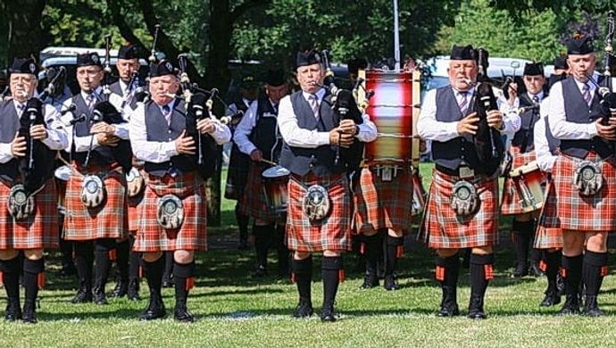 Group of people playing bagpipes dressed in kilts
