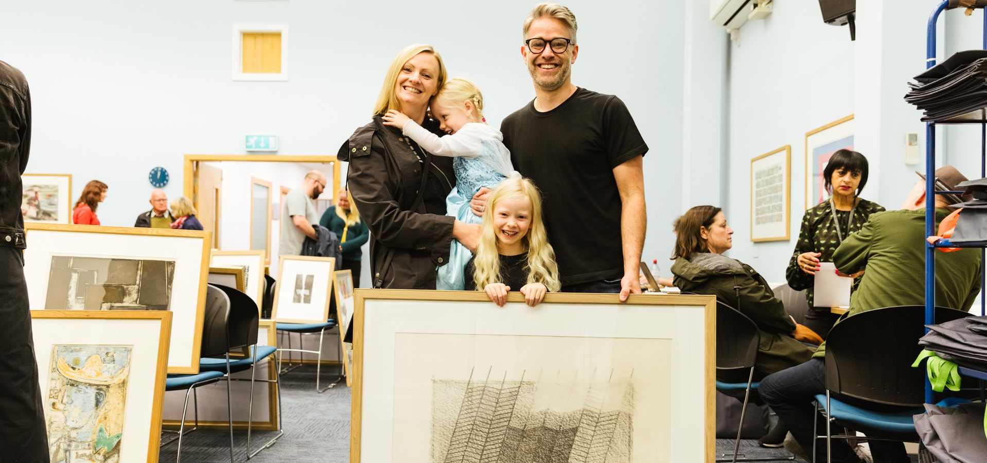 A couple and a child stood with their picture library print in Leeds Art Gallery