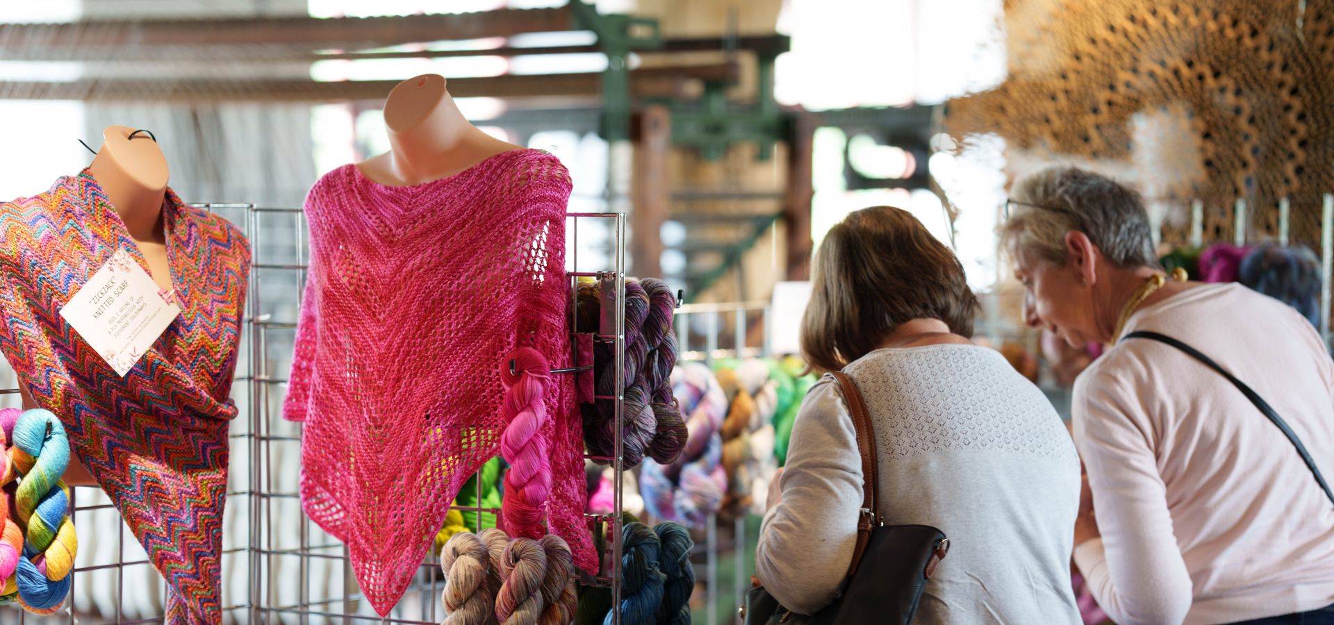 Two people browsing wool clothing stalls