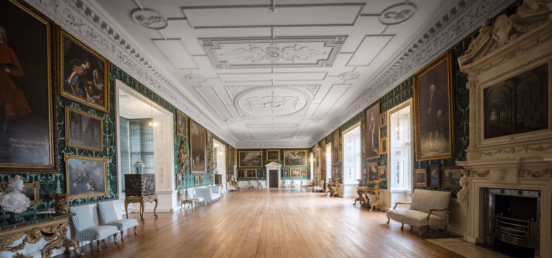 The picture gallery, with high ceilings and green walls with portraits hanging on them