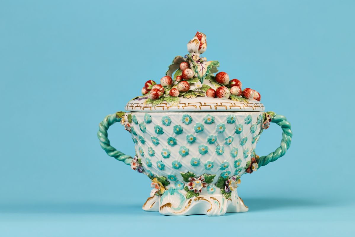 A ceramic pot with blue flowers around the base, blue handles and strawberries on the lid