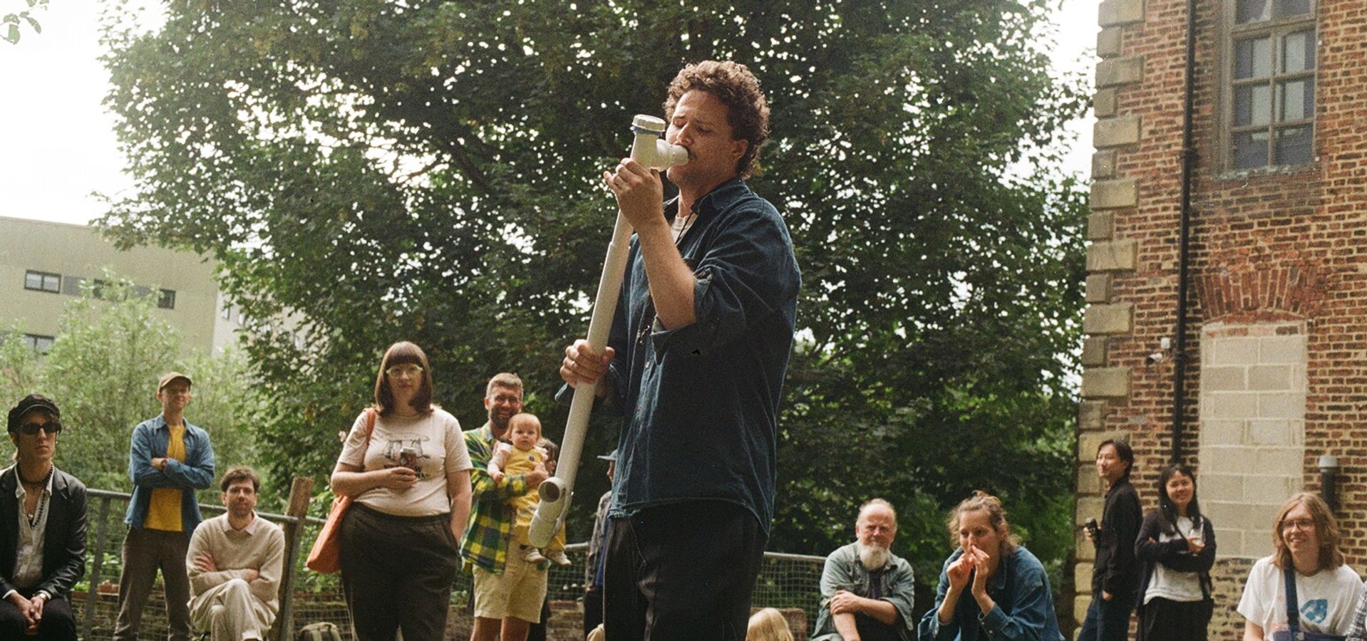 A person using a drain pipe as a musical instrument outdoors