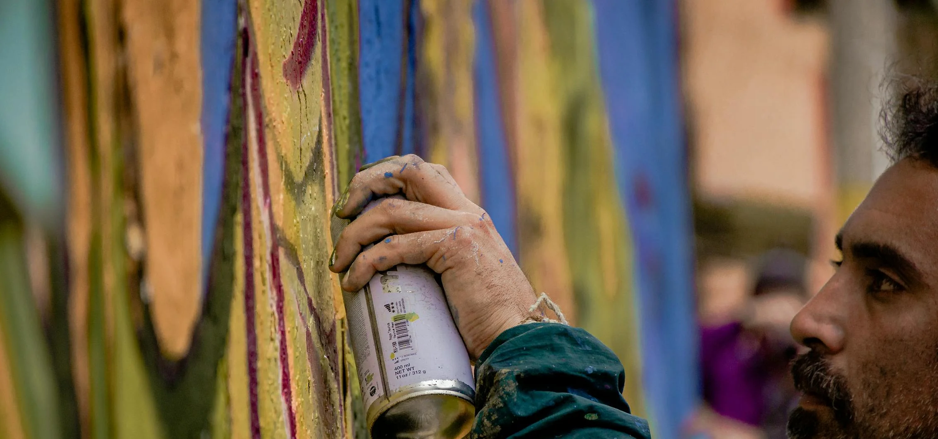 An artist spray painting a mural on a wall