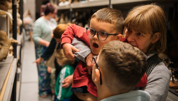 an adult holding a child up to look at an object