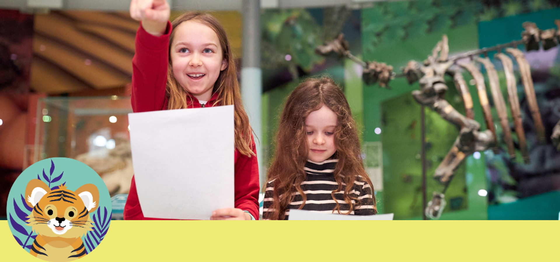 Two children holding trail sheets, with an animal skeleton display behind