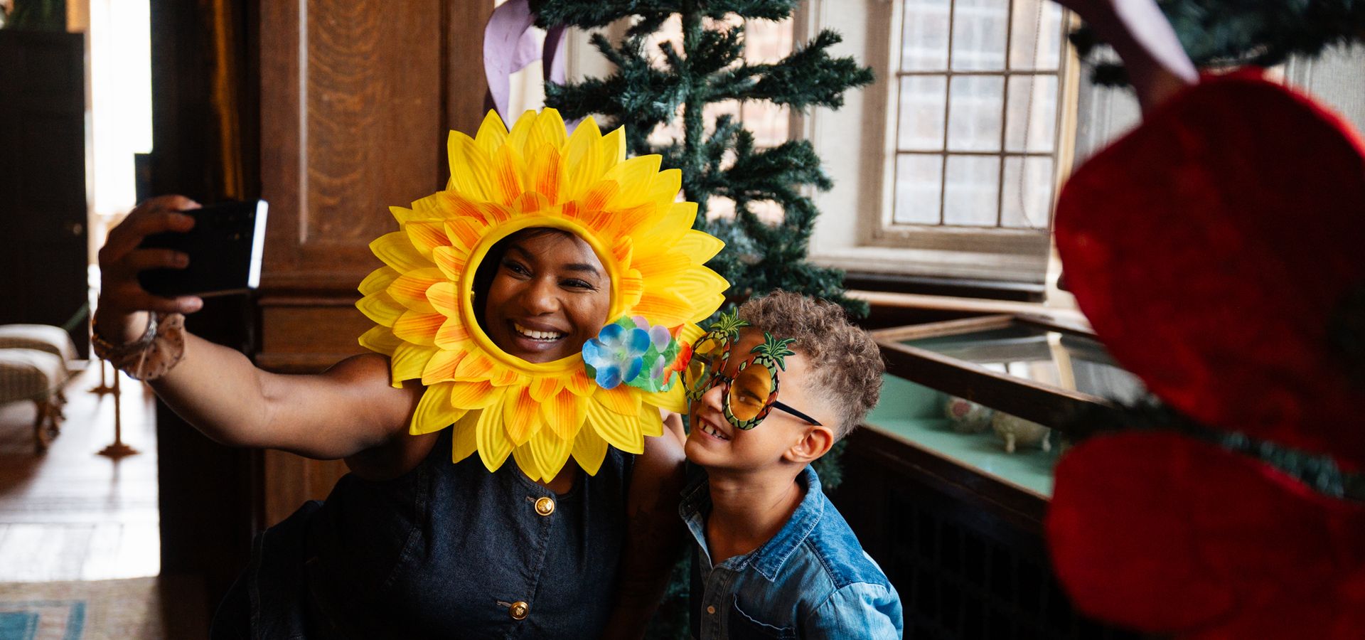 a woman with a sunflower face mask held to her face and a boy with plant themed sunglasses on taking a selfie