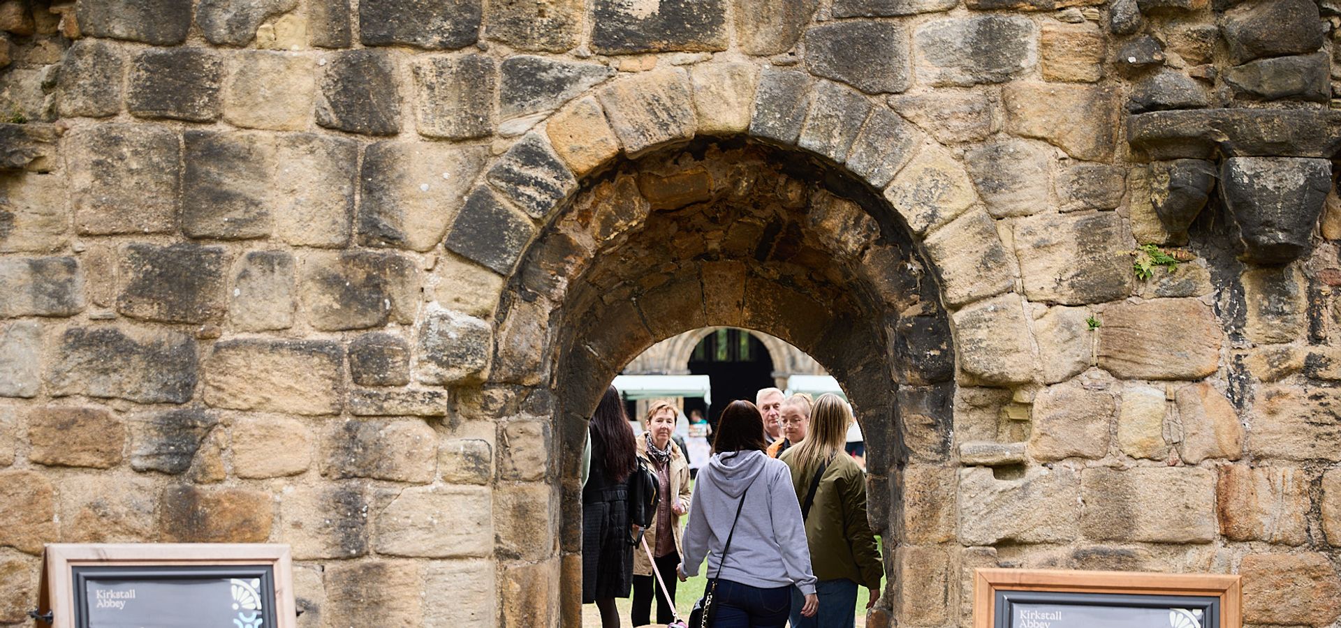 A group of people walking through an arch doorway at Kirkstall Abbey