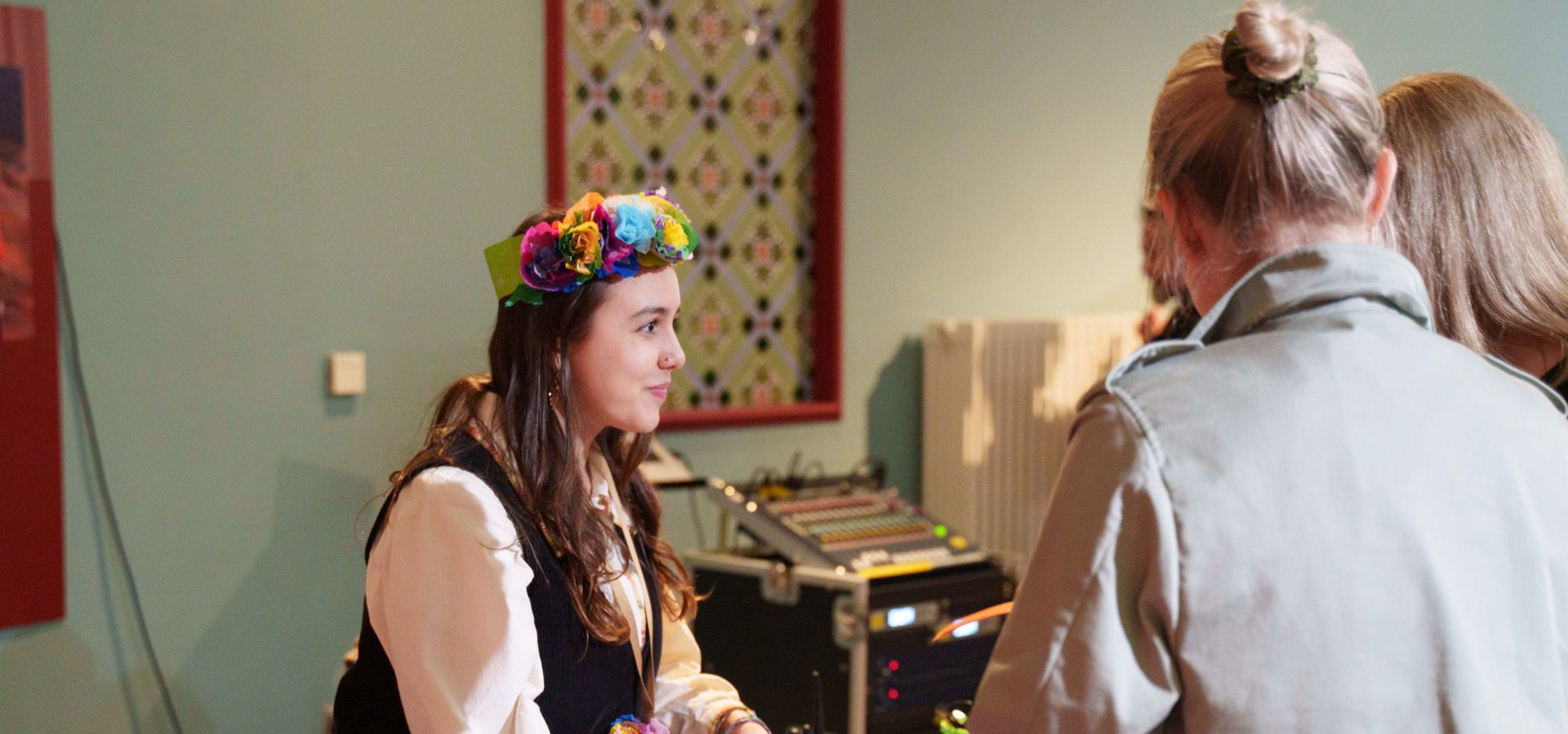 A woman leading a zine activity across a table with 2 people stood up