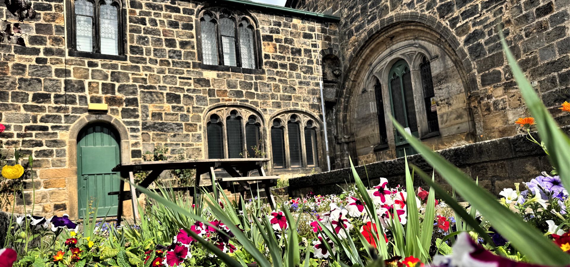 An old building with an archway of windows with flowers in front