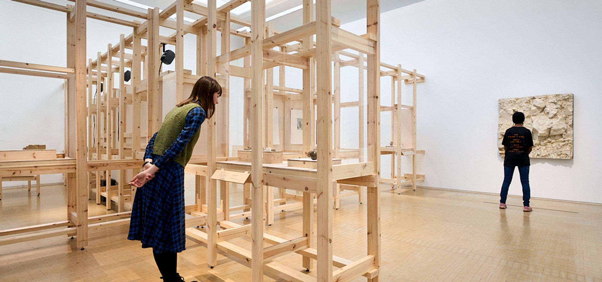 two people looking at artwork on a wooden stand