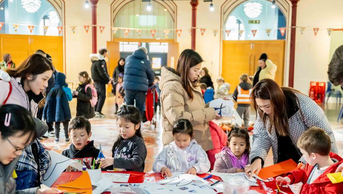 A group of adults and children doing craft activity around a table