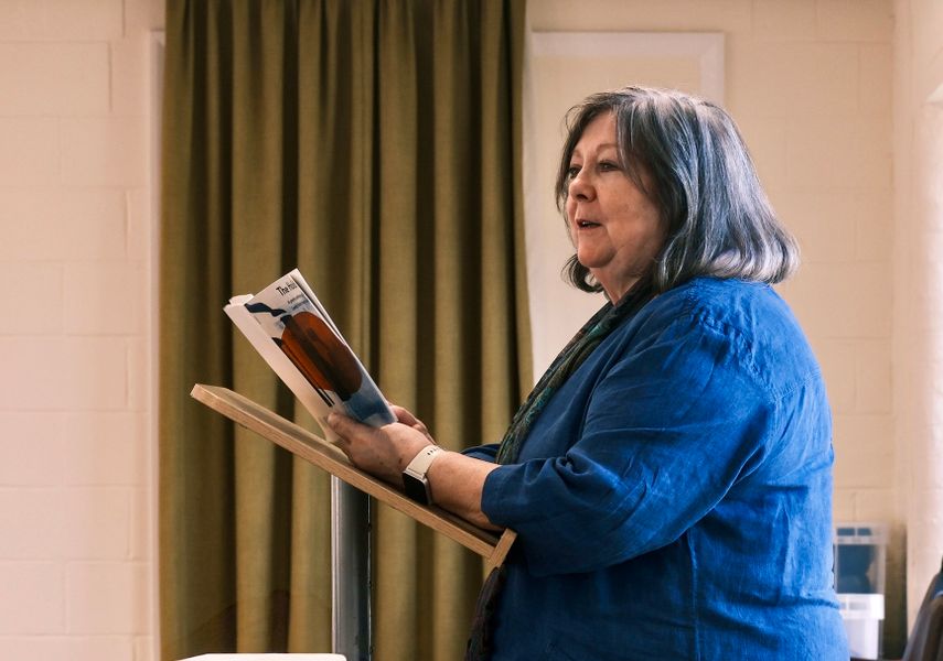 Woman holding 'The Holdings' book at a lectern