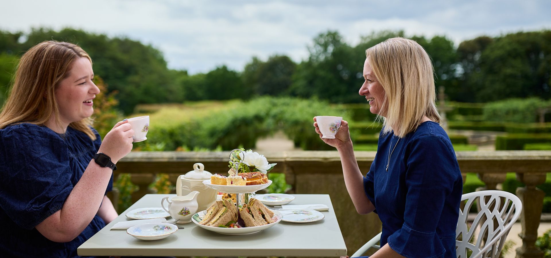 Two people sat at a table enjoying afternoon tea on Temple Newsam's terrace