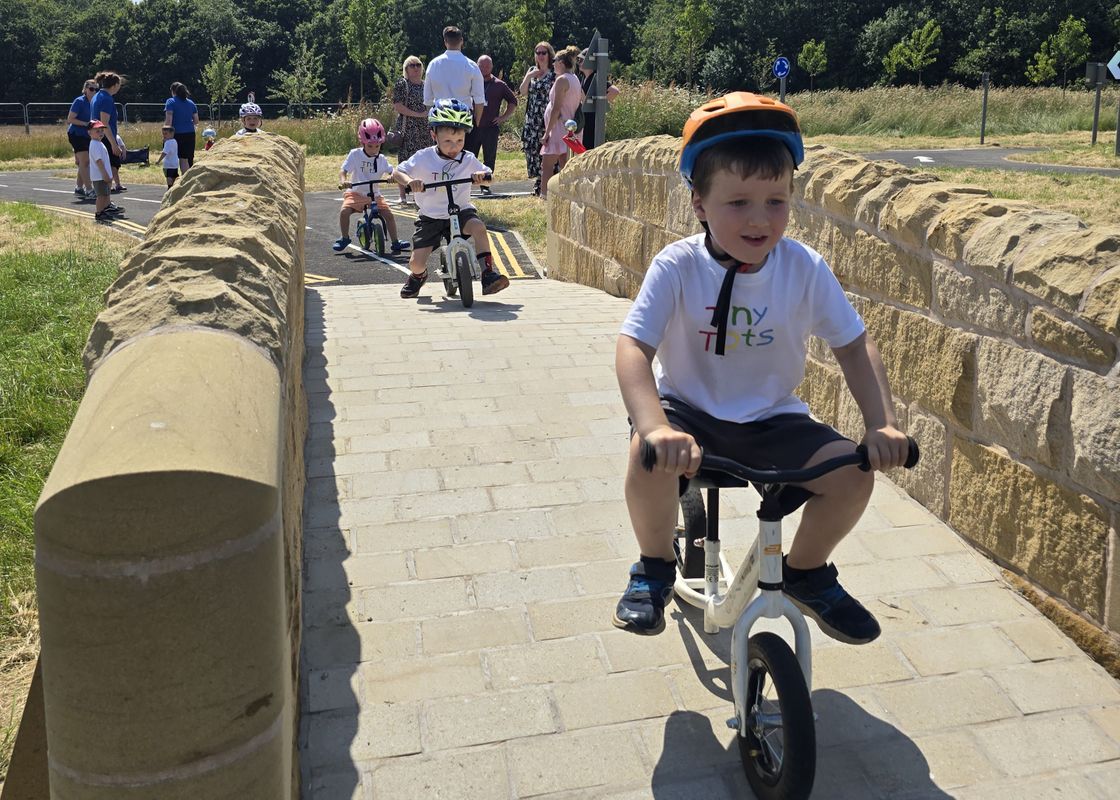 Children scootering and biking on the learn to ride area