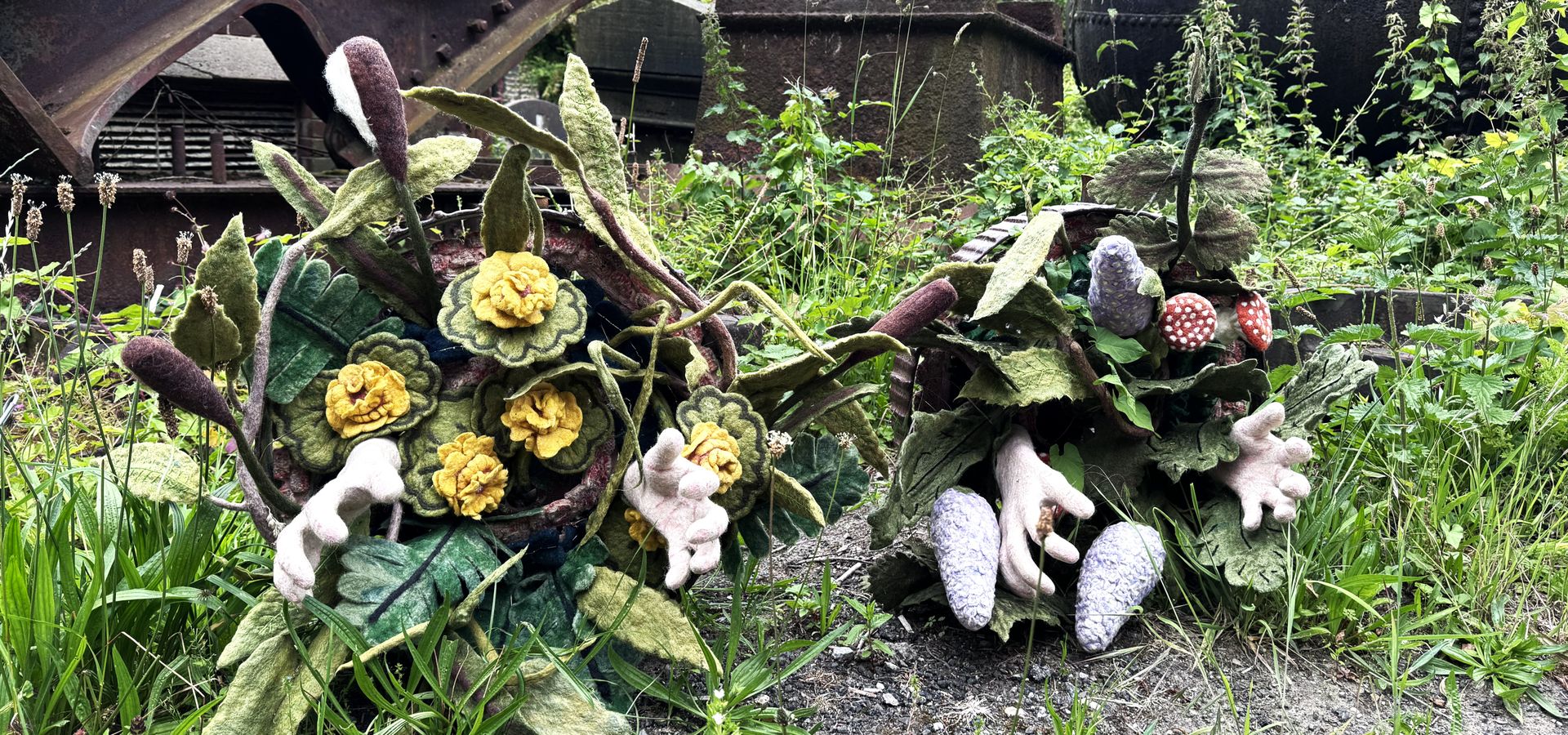 felted organic artwork surrounded by greenery in the gardens with machinery behind