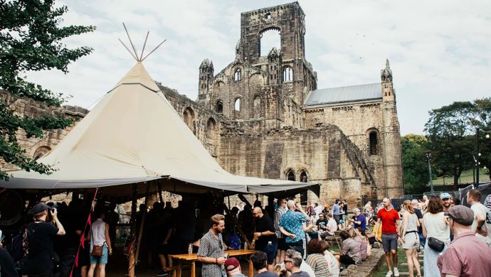 A crowd of people and a tipi in front of Kirkstall Abbey