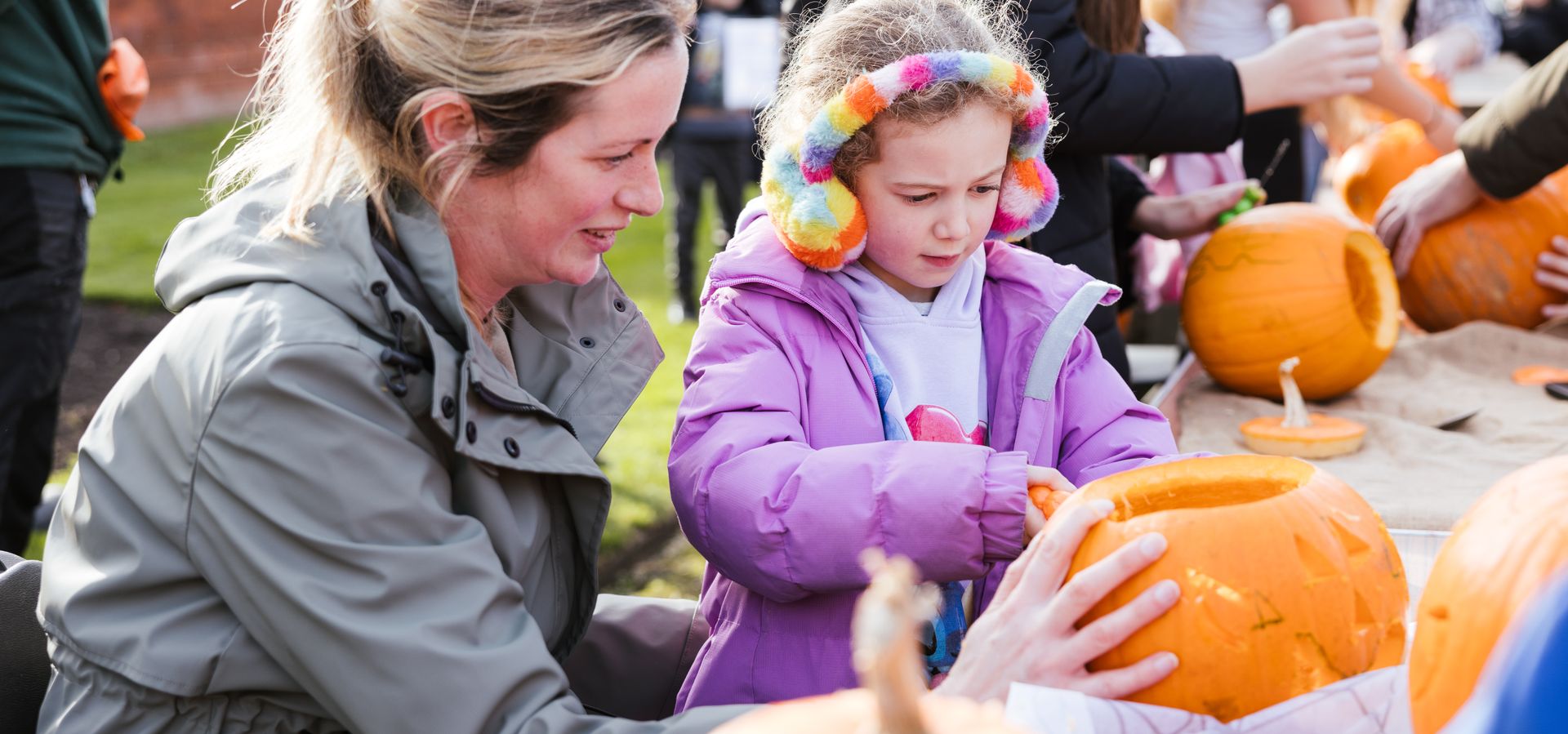 A woman and child carving a pumpkin at a table