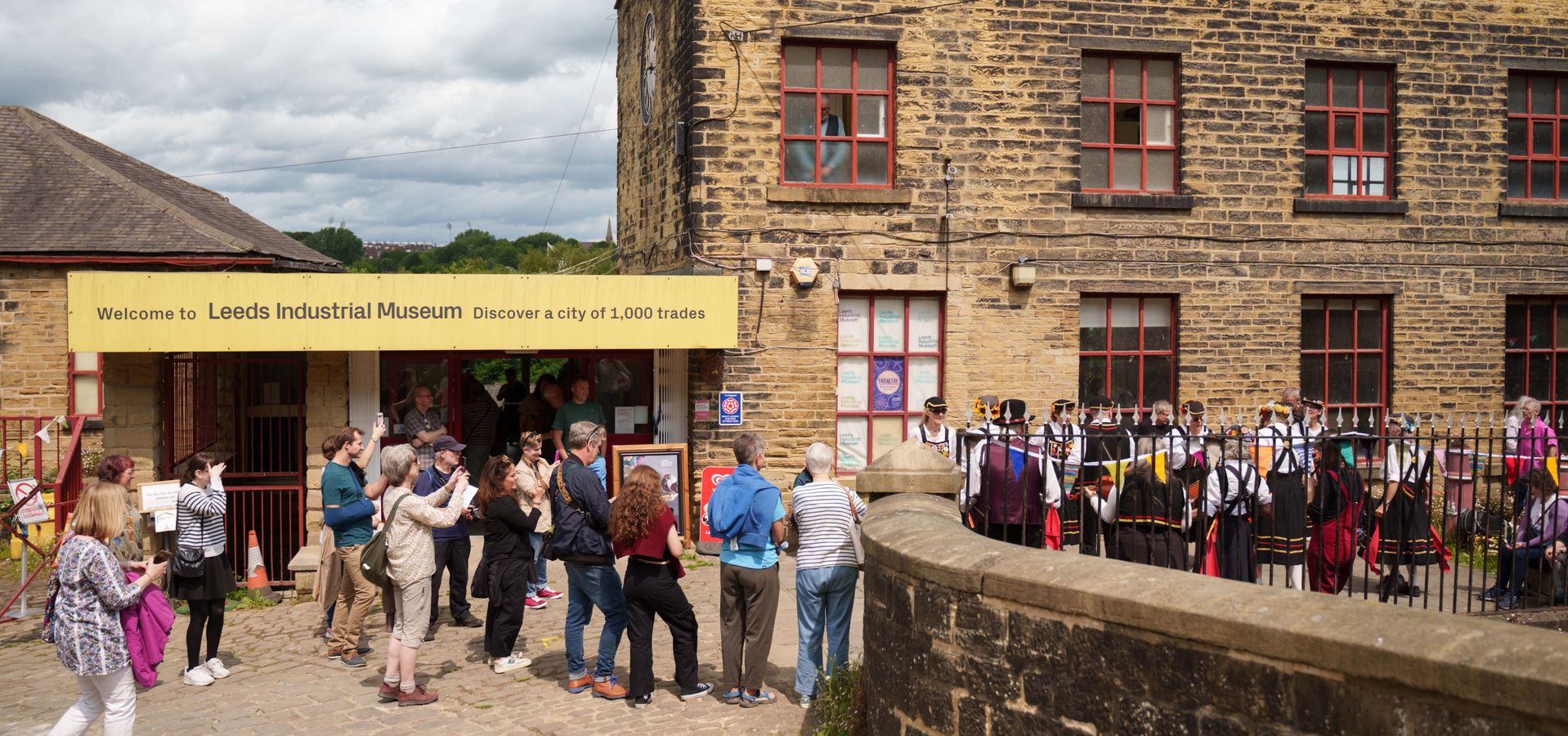 a large group of people stood outside the entrance to Leeds Industrial Museum watching a performance