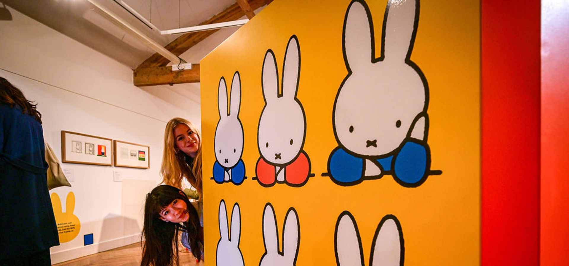 Two heads poking around the side of a large miffy book