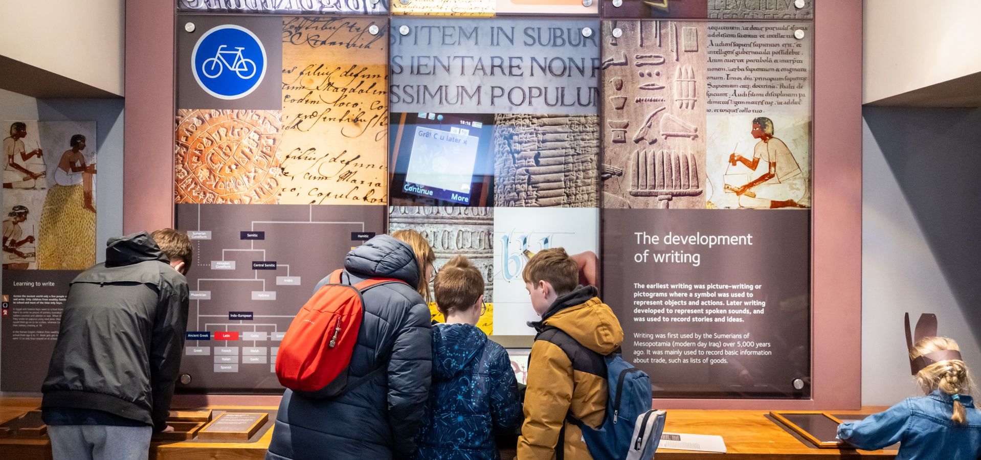 A group of people looking at an interactive element in the Ancient Worlds gallery at Leeds City Museum