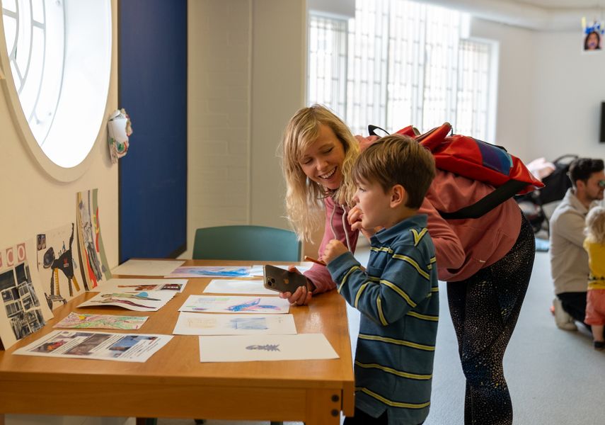 Parent and child looking at drawings on a table