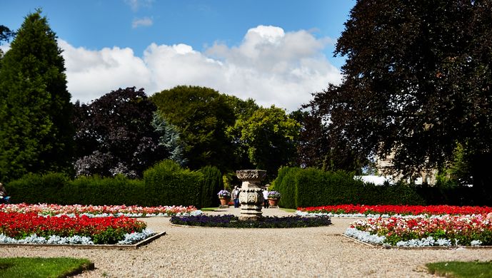 A stone pillar in a circle, with a pathway around and flower beds on all sides