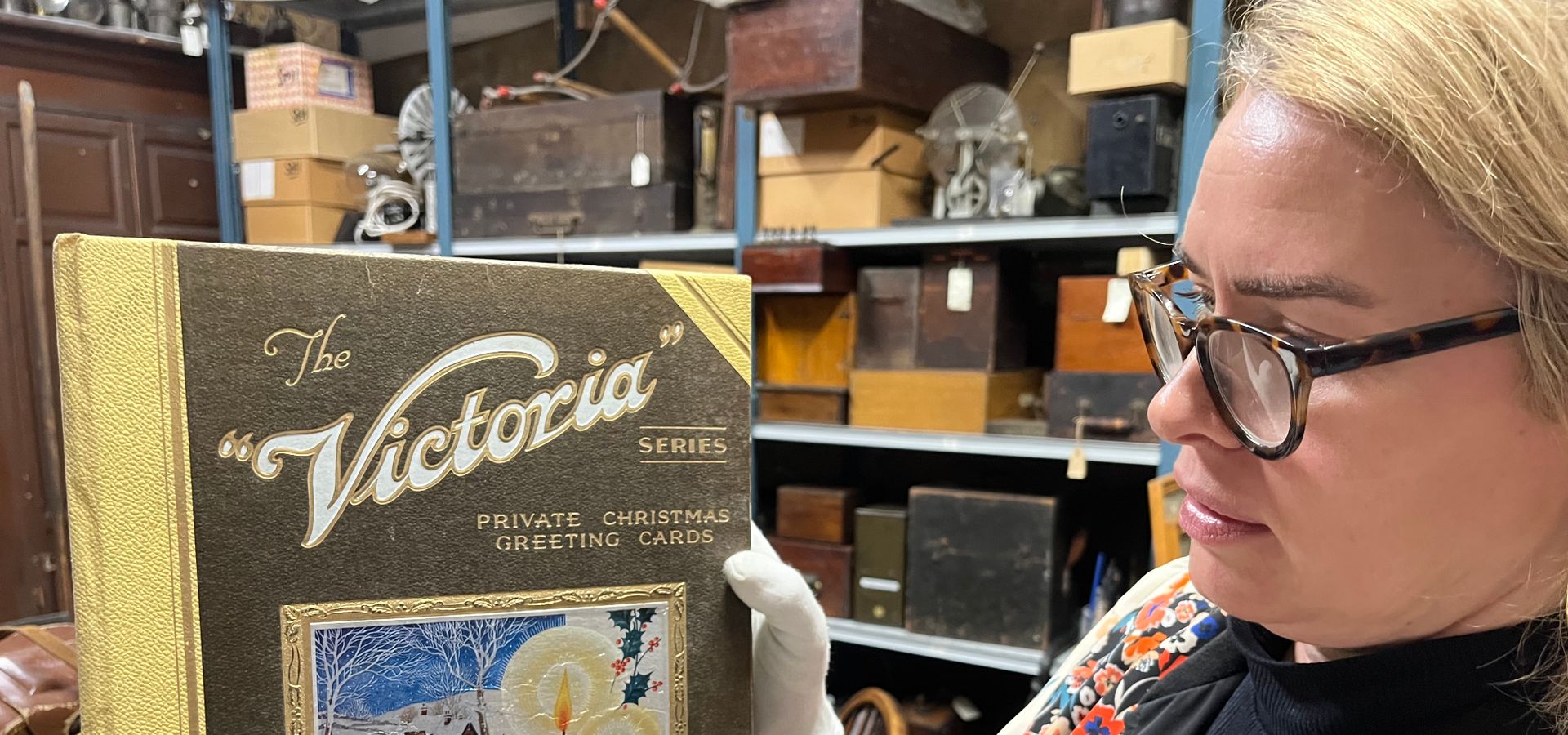 A curator holding a book with a snowy christmas image on titled 'the "Victoria" Series - private christmas greeting cards'