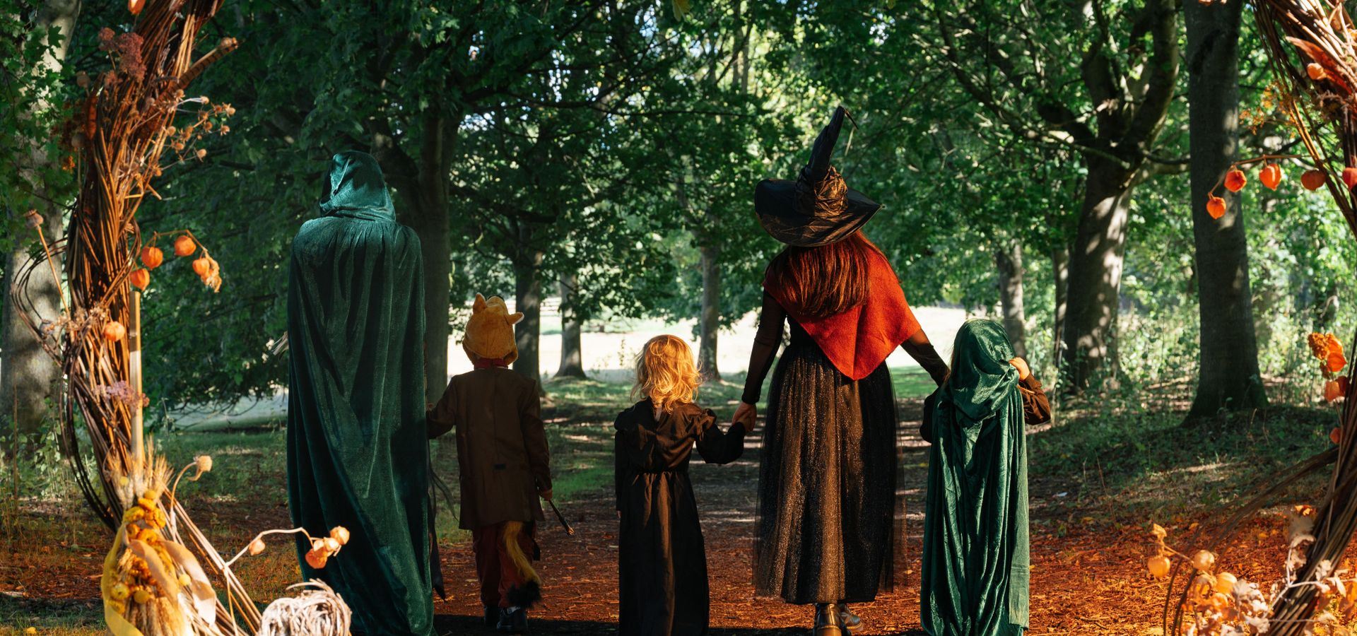 Two adults and 3 children dressed up as witches walking through a woodland