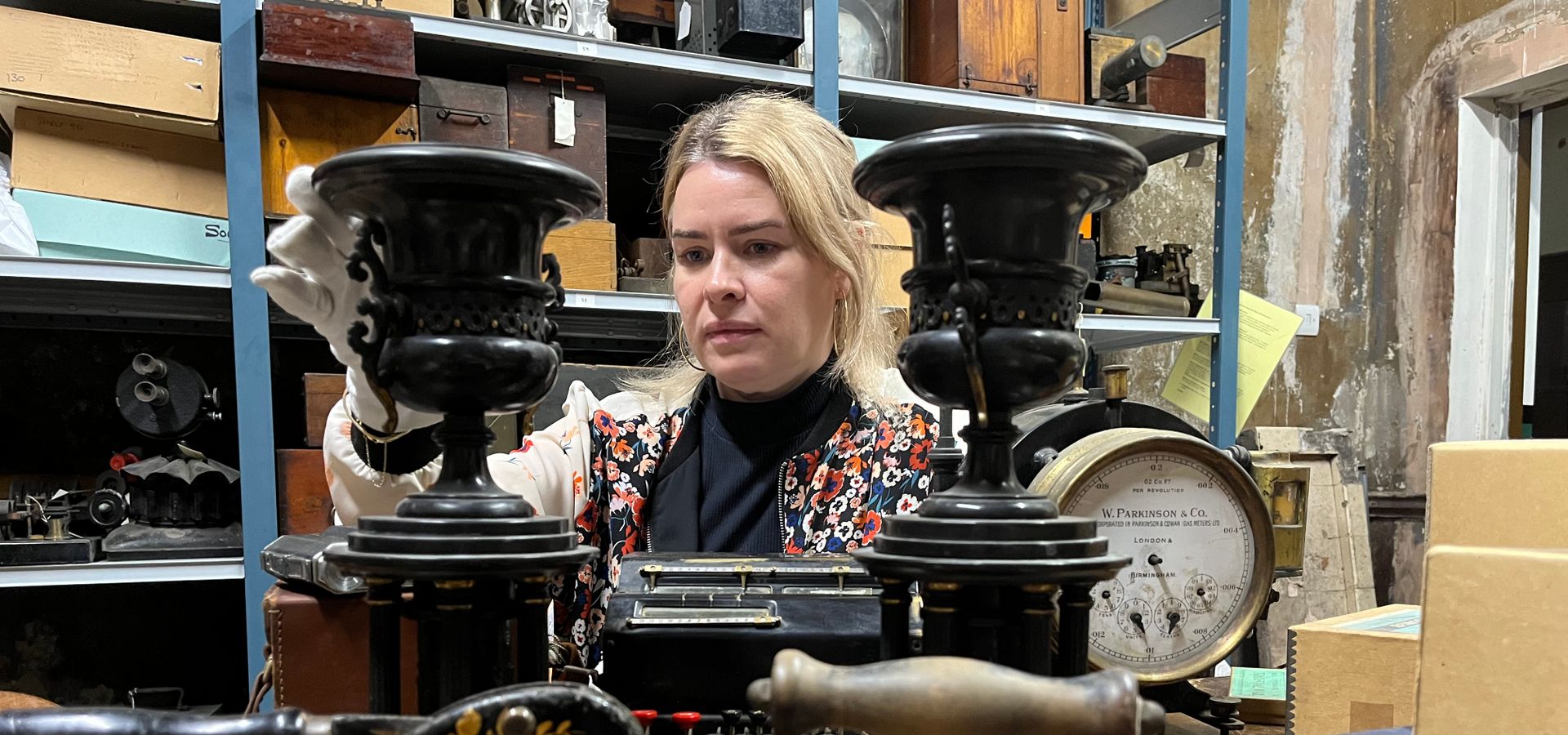 A curator looking at large metal objects from the collection