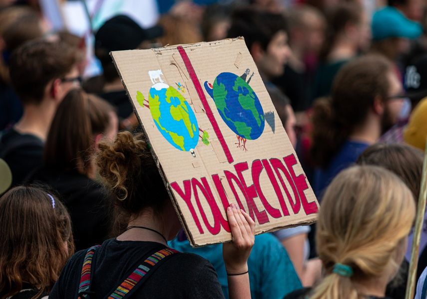 A protester holds up a cardboard sign with a climate change measure