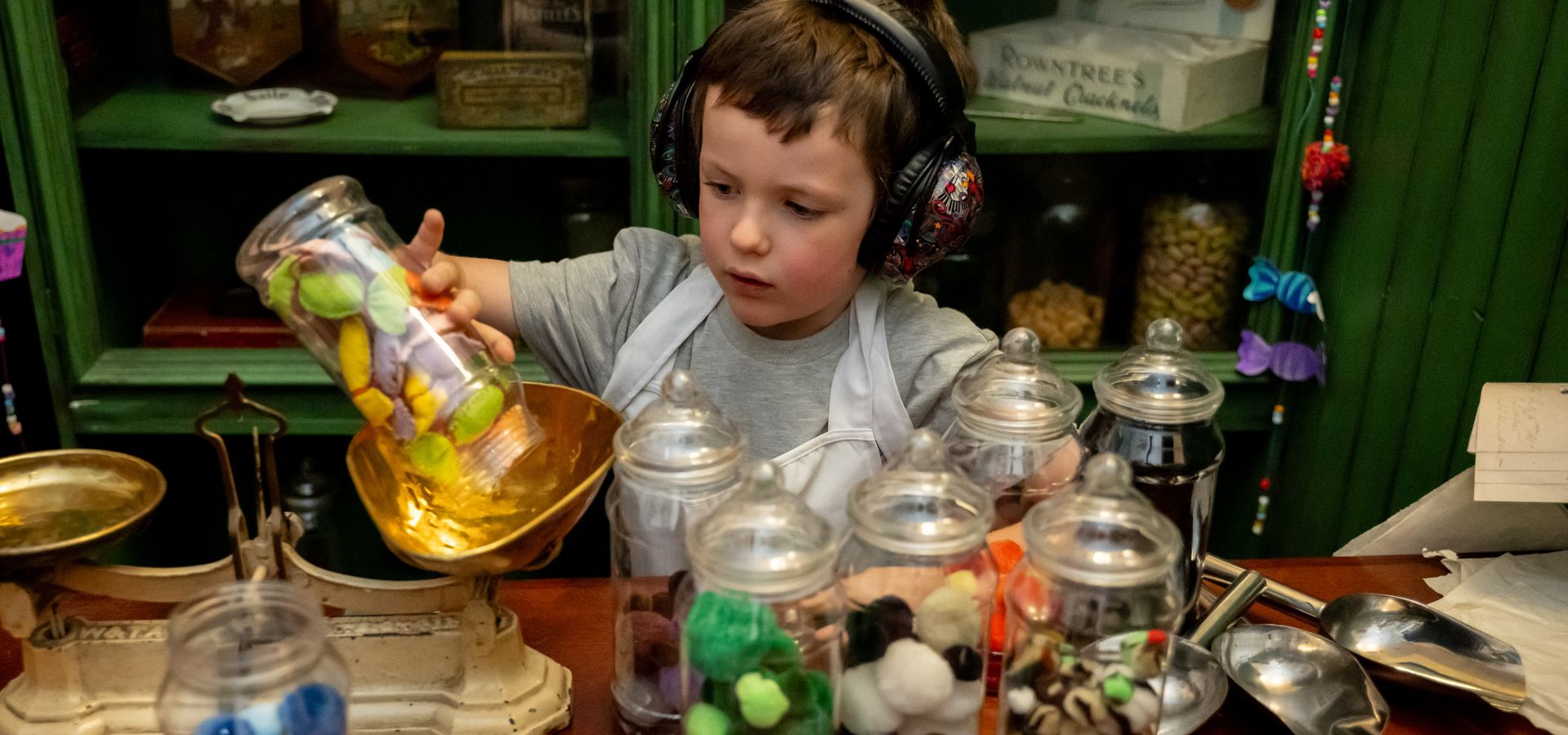 A child weighing pom pom sweets in clear containers