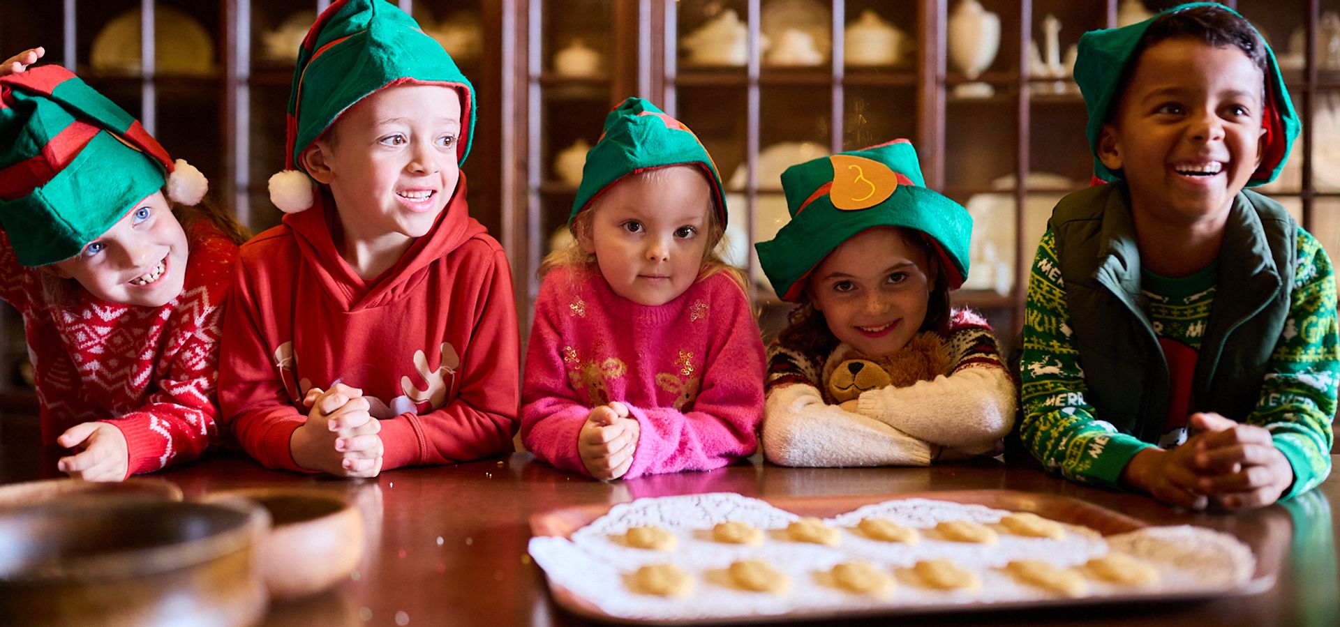 A group of children in elf hats making Christmas biscuits