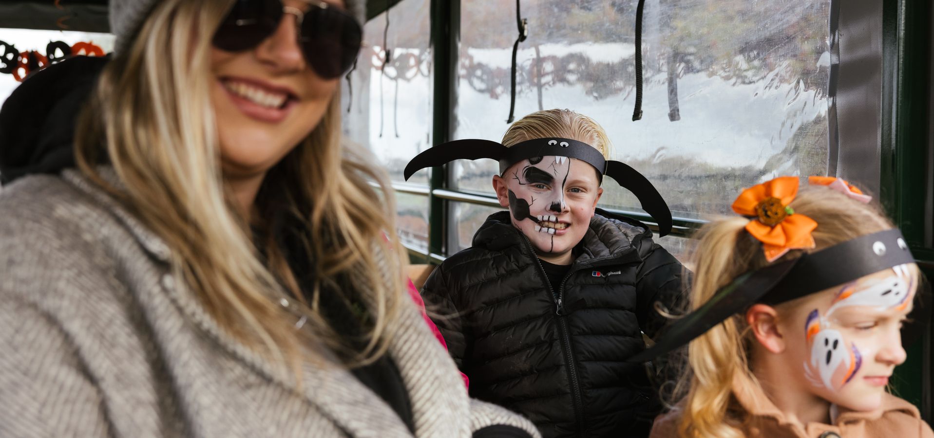 A woman in sunglasses and two children in face paint