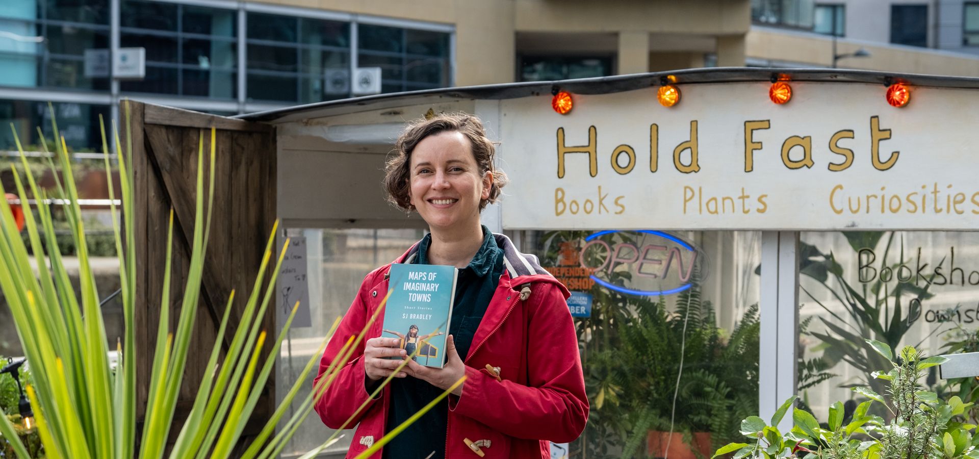 SJ Bradley holding her book on the HoldFast bookshop boat in Leeds
